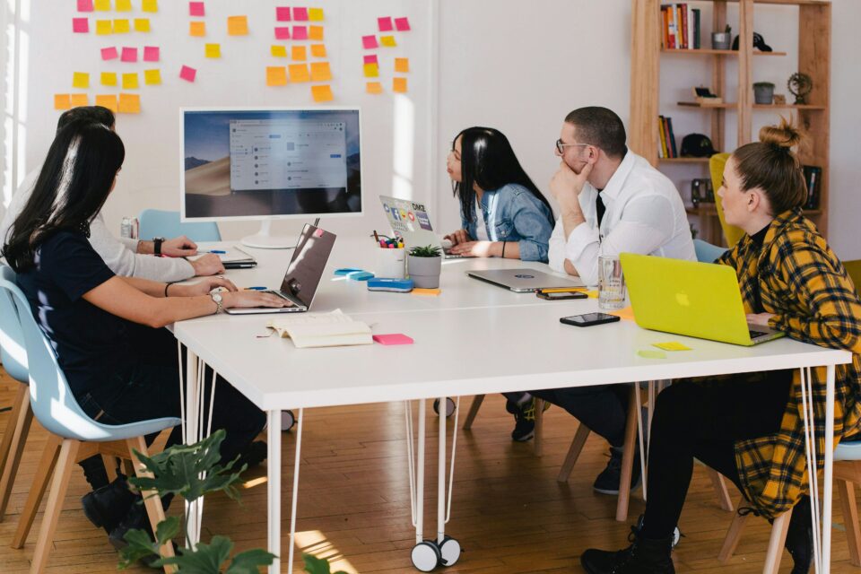 A group of people at a desk looking a screen on the board