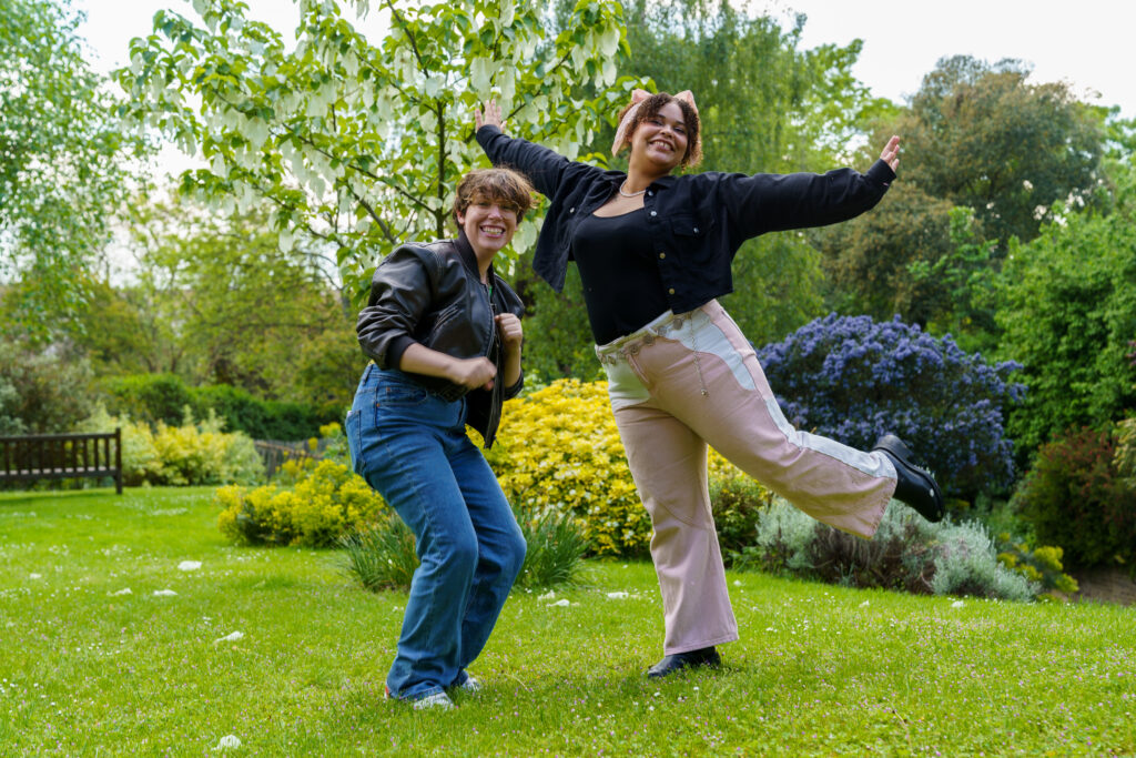 Two people smiling and posing for the camera outside 