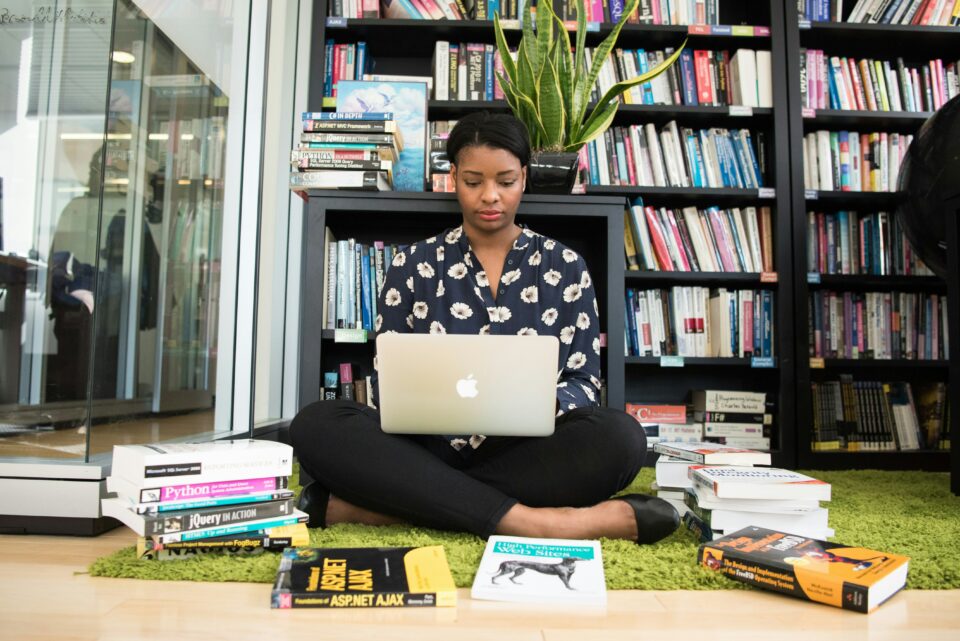 A woman sitting on the floor with books laying around her