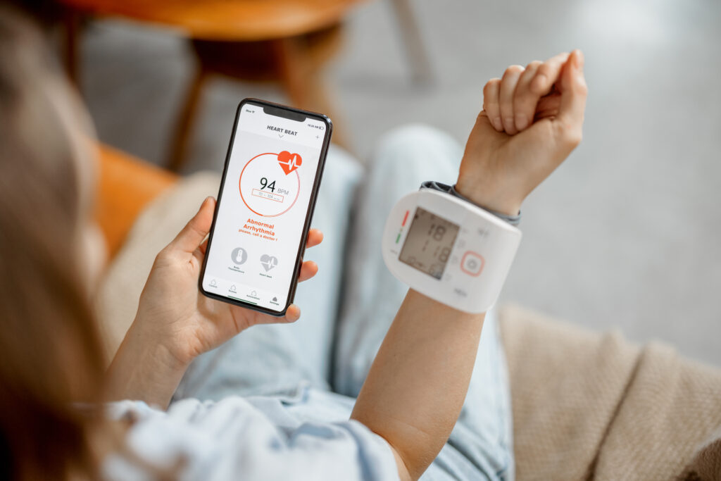 Woman measure heart rate and pressure with smart technology in phone while sitting on sofa at home. Health and wellness concept.