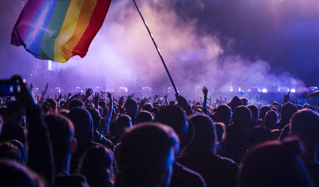 Pride community at a parade with hands raised and the LGBT flag - symbol of love and tolerance