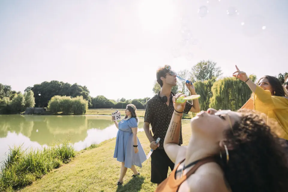 Group of friends blowing bubbles in park