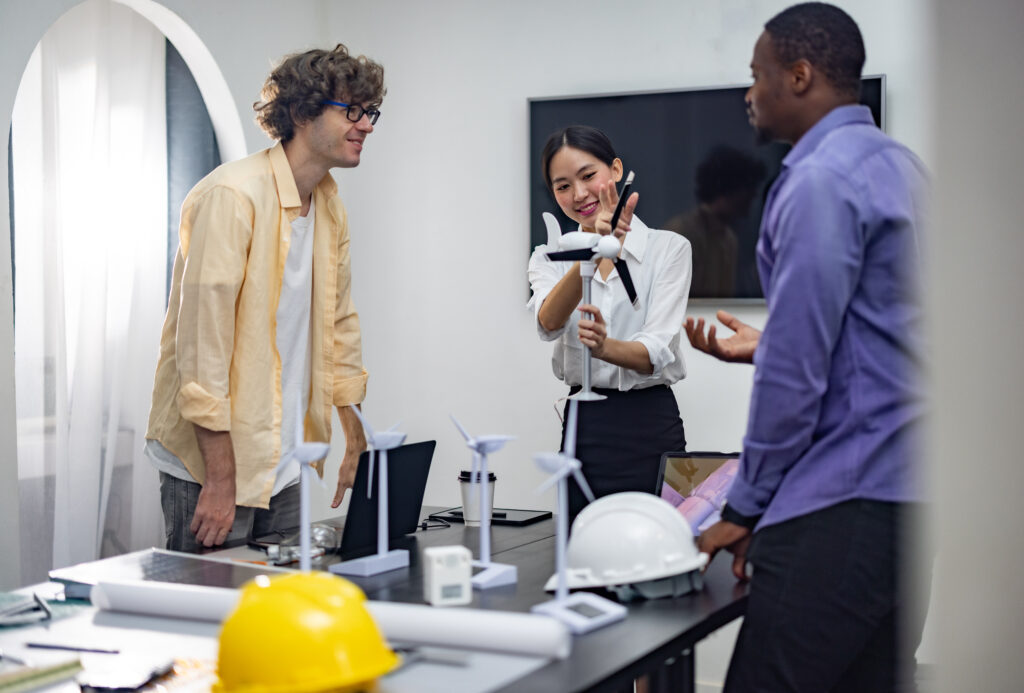 A diverse startup team develop, collaborates on a powerful, lightweight, portable wind turbine prototype, aligning with potential user demand and renewable energy needs to secure investor funding.