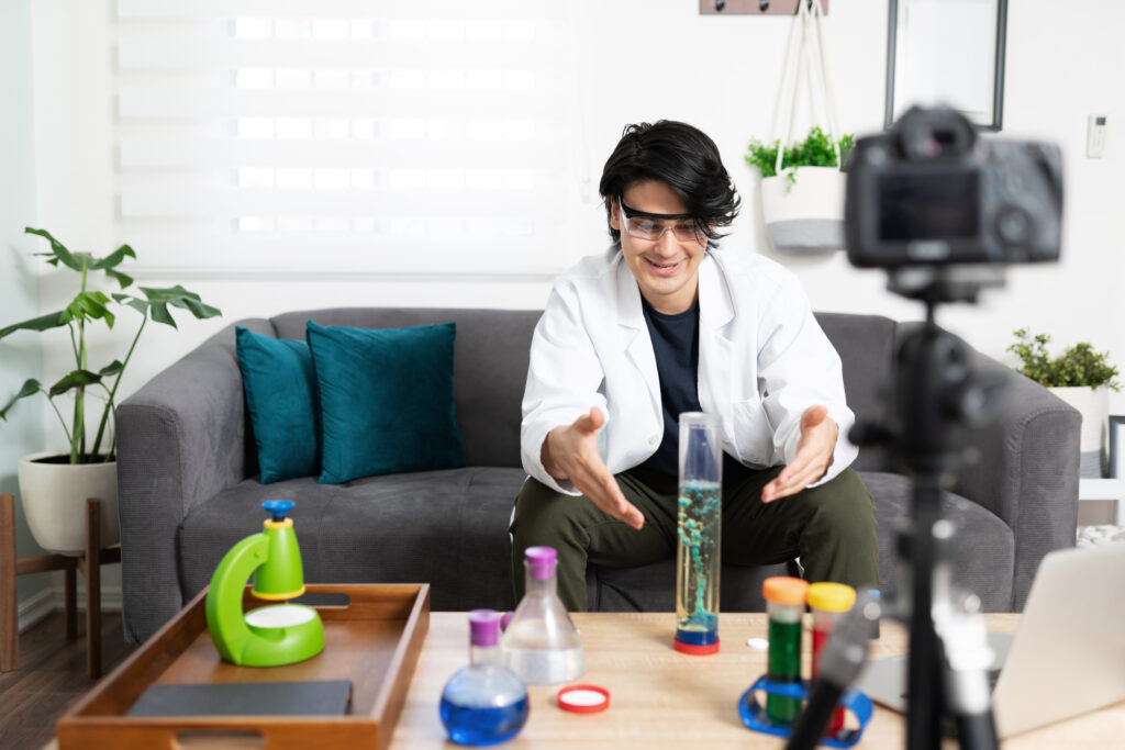 Latin influencer and video blogger wearing lab coat and demonstrating a science experiment for his social media followers