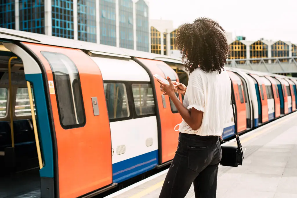Picture of an underground train at a station and a woman standing in front of it
