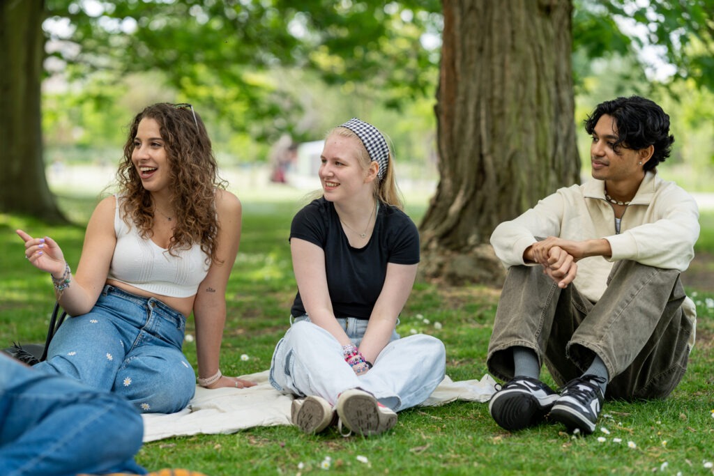 Students sitting on the grass in a park having a conversation-living in London