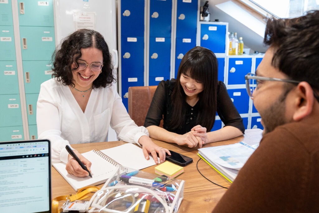 someone writing down school related work with 2 friends indoors showing life in London