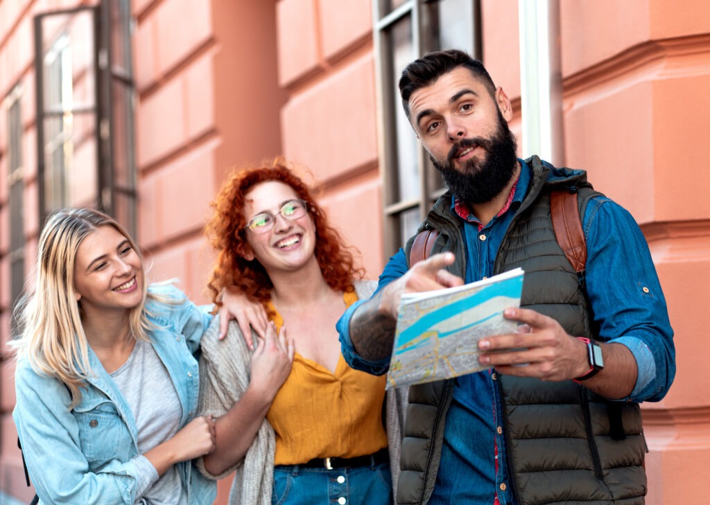 3 friends exploring a street and one friend holding a map in hand and showing the way