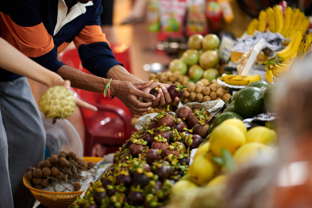 An image of a young male student picking fruits in a market